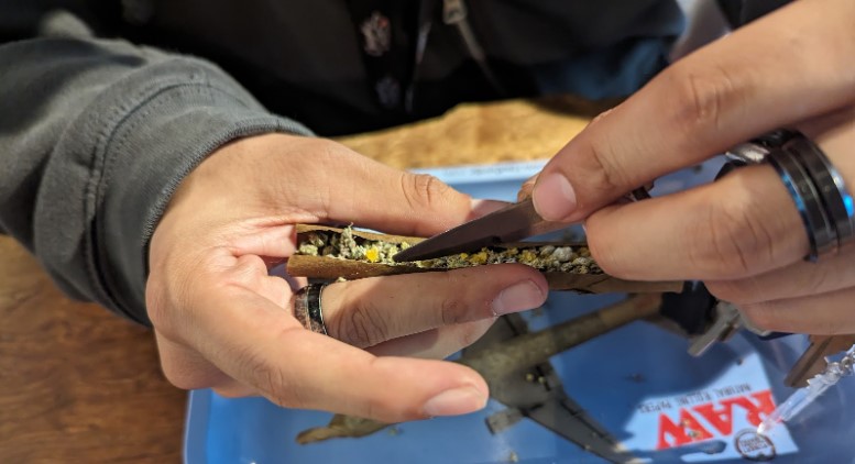 image of using a knife to push cannabis flower into an infused cannabis cigarette